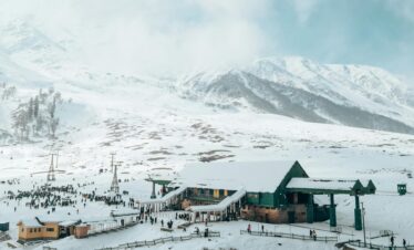 Aerial view of Gulmarg resort with snowy mountains, perfect winter travel destination.