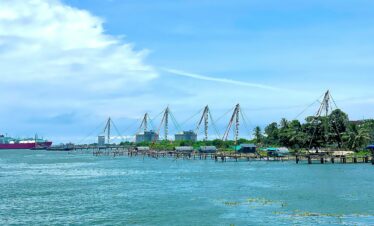 Traditional Chinese fishing nets line the waterfront in Cochin, India on a bright summer day.