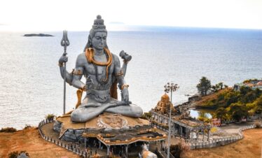 A stunning aerial view of the Murudeshwara Temple with the iconic Shiva statue by the sea.