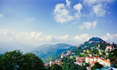 Picturesque view of Shimla's mountains and townscape under a clear blue sky.