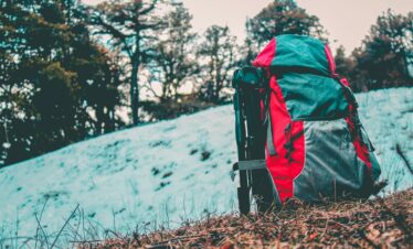 A vibrant backpack rests on a snowy trail in Shimla. Perfect for adventure and nature enthusiasts.