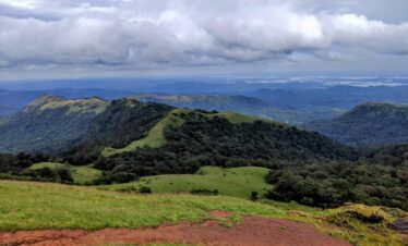 Vast view of lush green mountains under a cloudy sky in the Western Ghats, India.