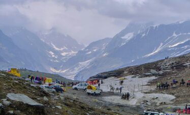 Majestic view of Rohtang Pass with tourists and vehicles amidst the snow-capped Himalayas.