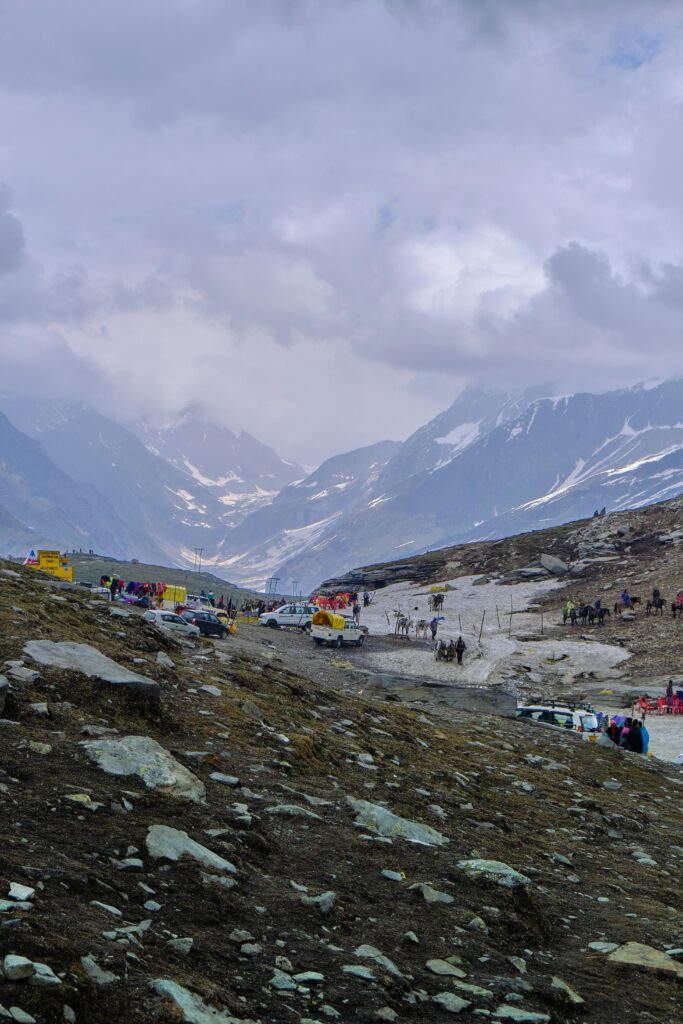 Majestic view of Rohtang Pass with tourists and vehicles amidst the snow-capped Himalayas.