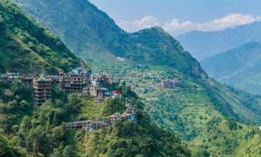 Explore the stunning aerial view of Rishikesh with its lush green mountains and vibrant town nestled in nature.