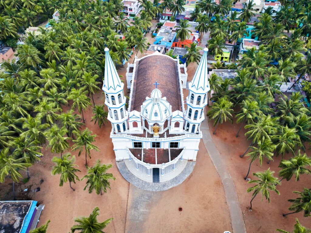 Stunning aerial shot of a white church with twin towers, nestled among palm trees in Kanyakumari, India.