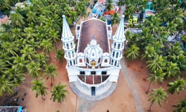 Stunning aerial shot of a white church with twin towers, nestled among palm trees in Kanyakumari, India.