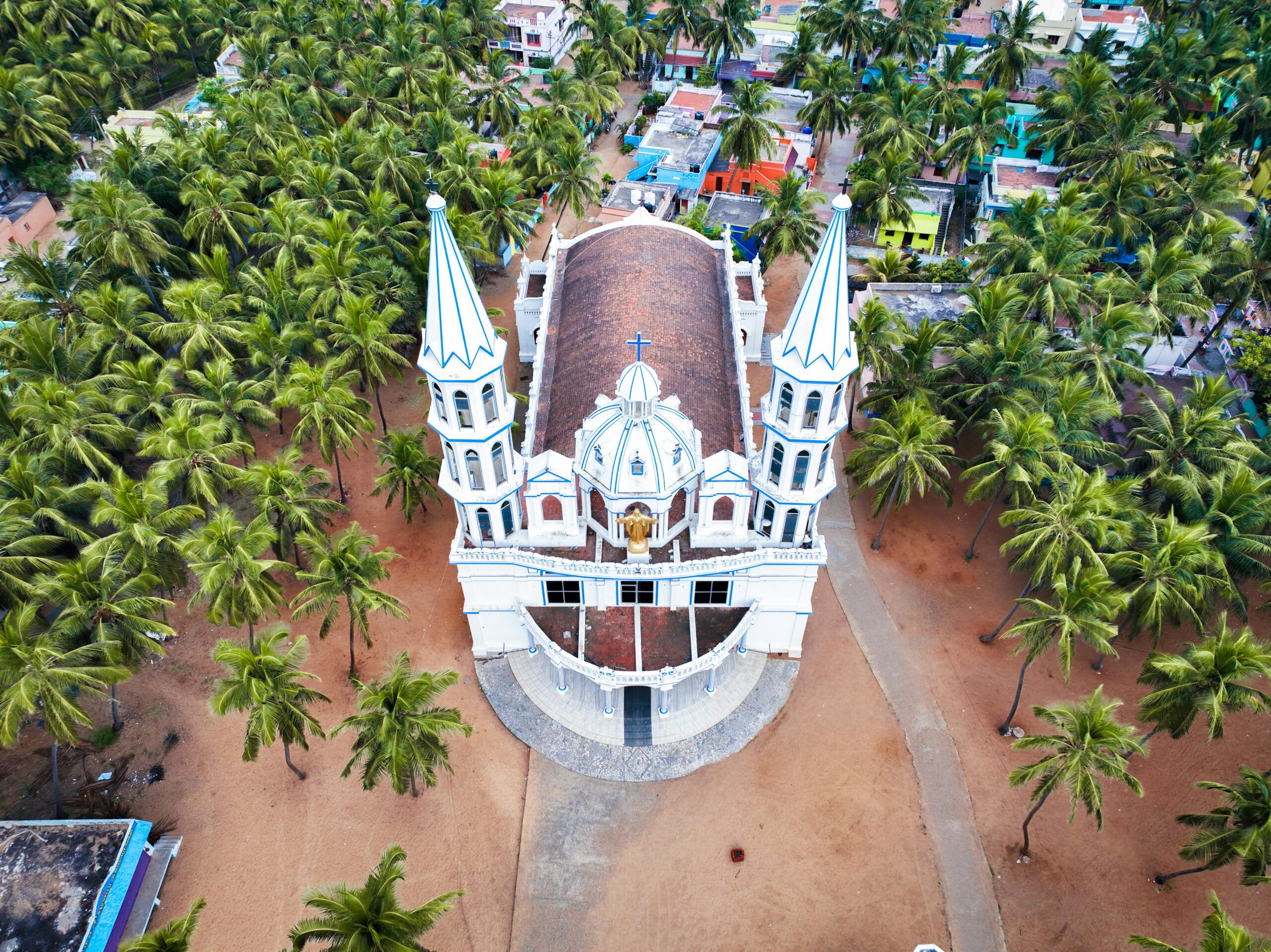 Stunning aerial shot of a white church with twin towers, nestled among palm trees in Kanyakumari, India.