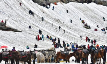 Crowd engaging in winter activities in Kedarnath's snowy landscape.