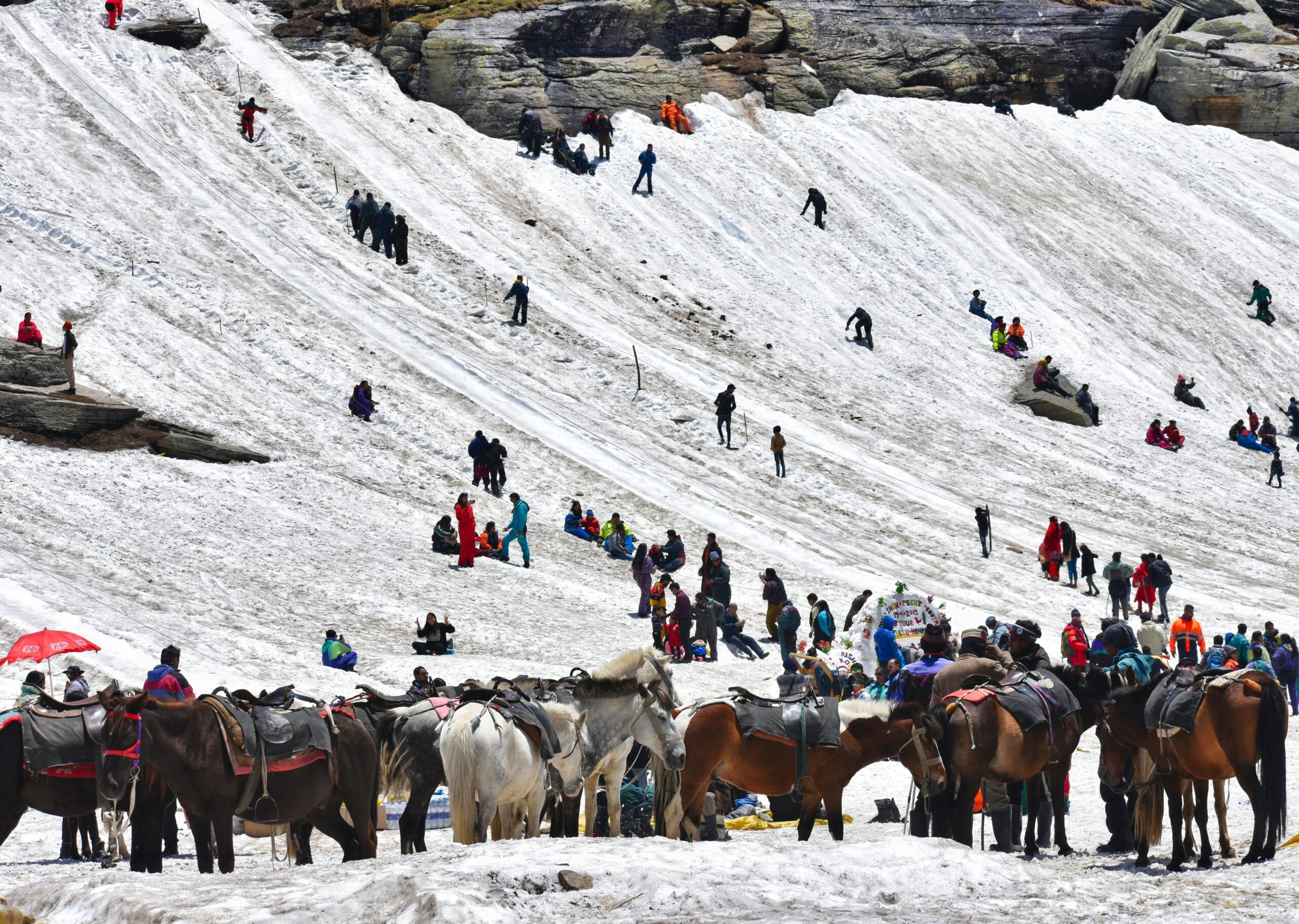 Crowd engaging in winter activities in Kedarnath's snowy landscape.