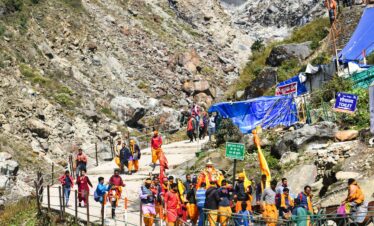 Colorful procession of pilgrims walking along the rocky path in Kedarnath, India.