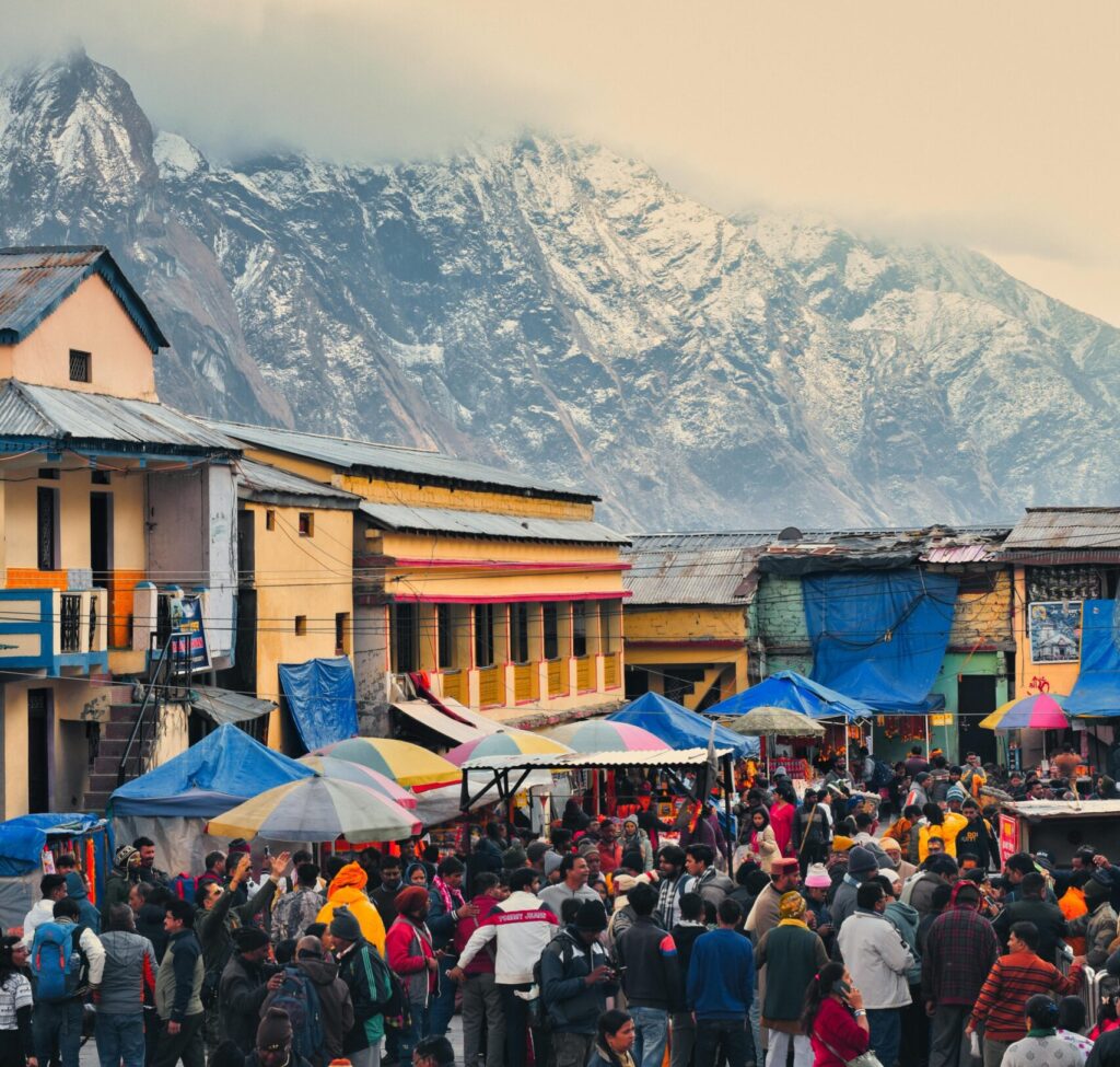Vibrant market scene in Kedarnath, India, with snow-capped mountains in the background.