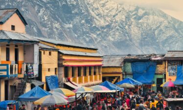 Vibrant market scene in Kedarnath, India, with snow-capped mountains in the background.