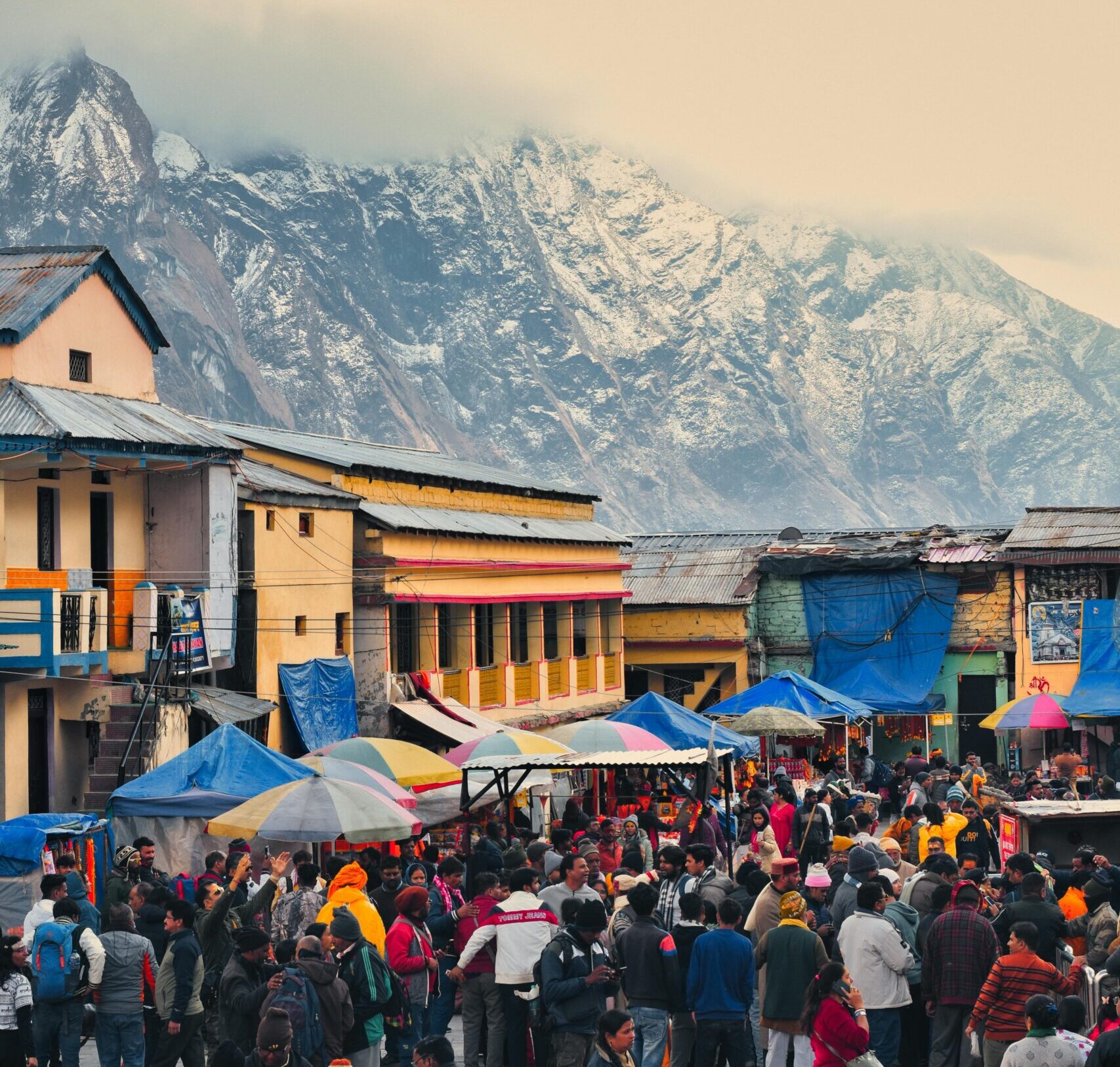 Vibrant market scene in Kedarnath, India, with snow-capped mountains in the background.