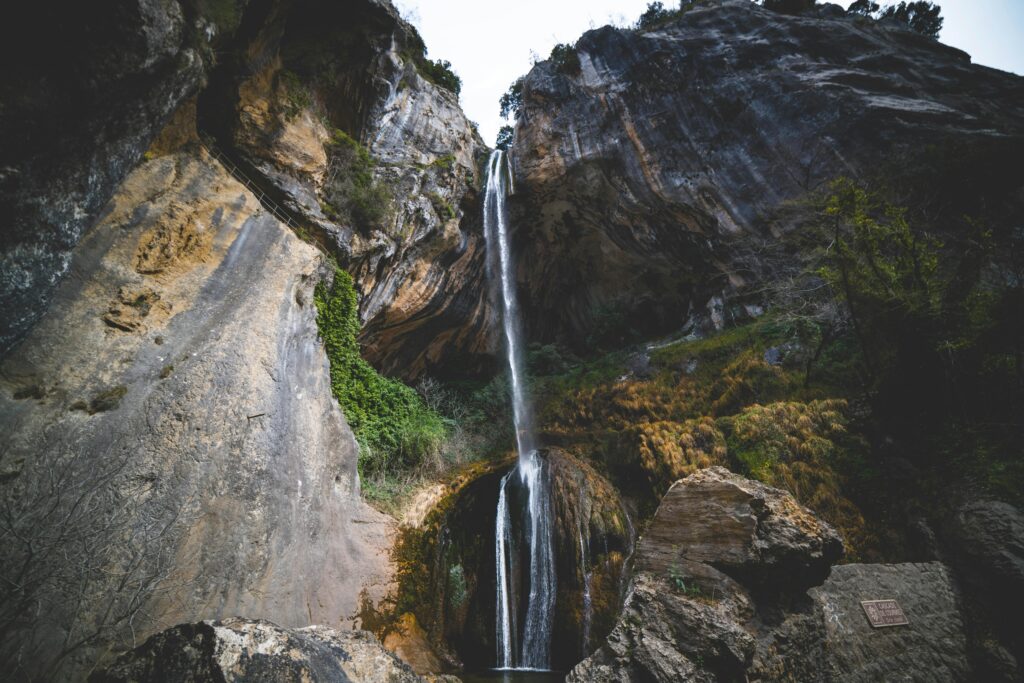 Breathtaking view of a waterfall cascading down rocky cliffs in Courmes, France.