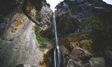 Breathtaking view of a waterfall cascading down rocky cliffs in Courmes, France.
