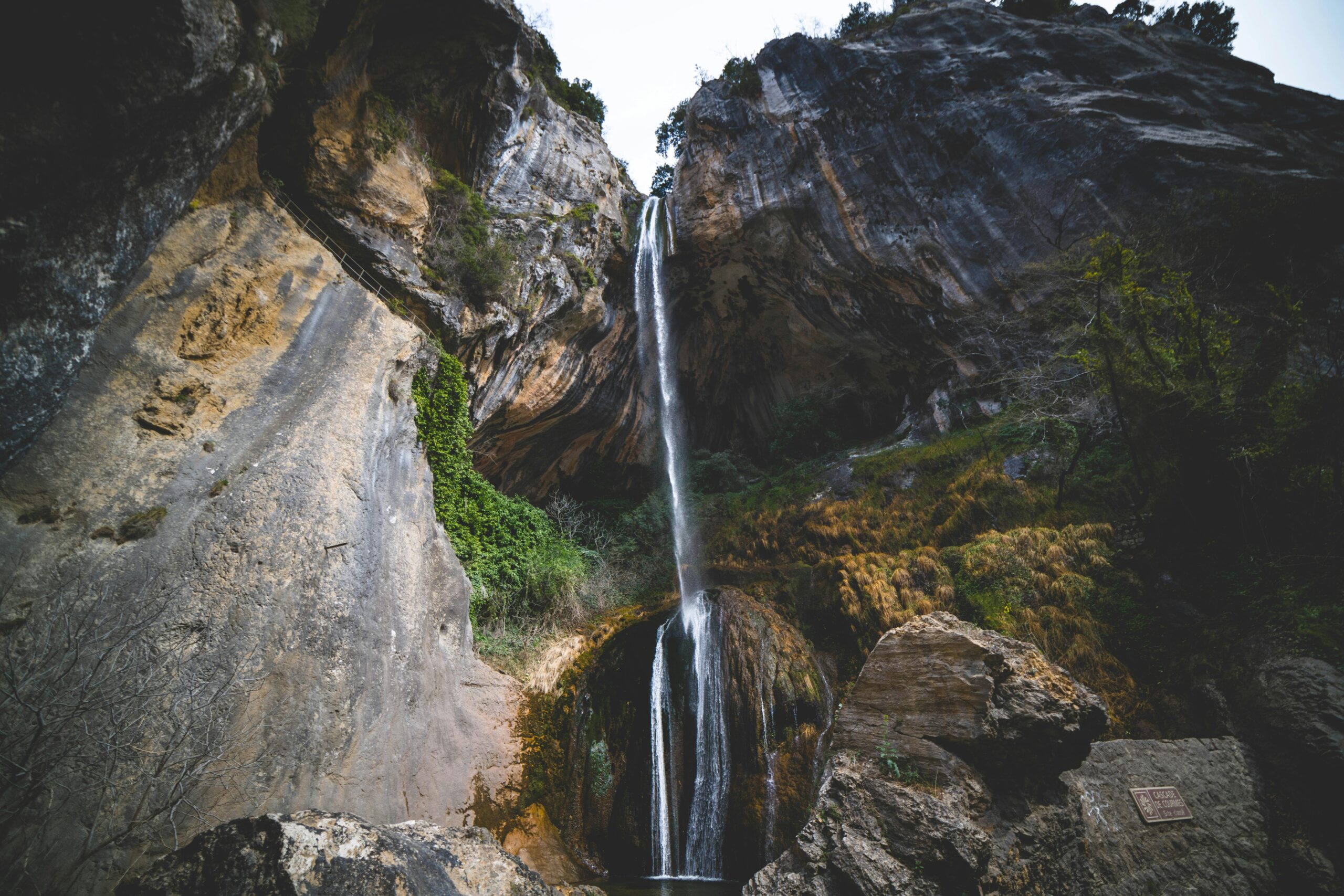 Breathtaking view of a waterfall cascading down rocky cliffs in Courmes, France.
