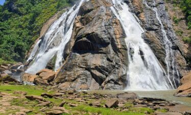 Stunning view of Dudhsagar Waterfall cascading down rocky cliffs during a summer day.