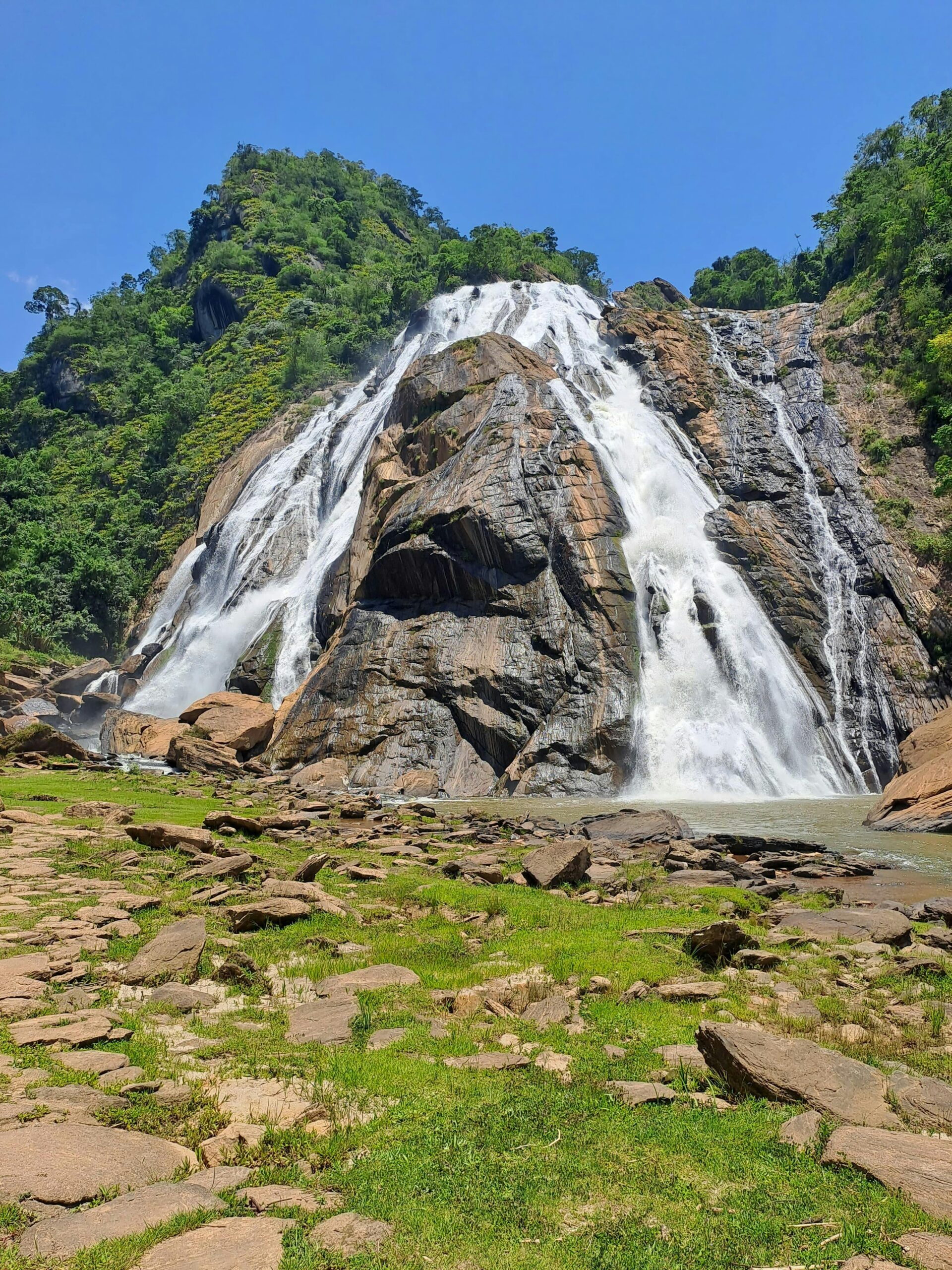 Stunning view of Dudhsagar Waterfall cascading down rocky cliffs during a summer day.