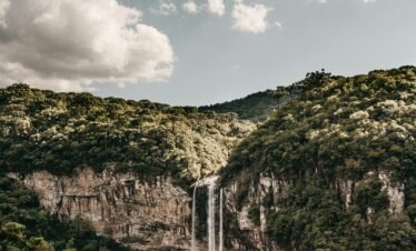 Explore the majestic Caracol Falls set amid dense Brazilian forests under a cloudy sky.