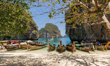 Idyllic beach scene with boats docked at Krabi, Thailand, and beautiful rock formations.