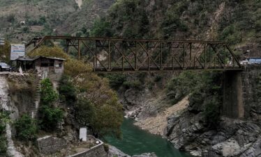 Explore the rustic beauty of a bridge over a river, nestled in the Himalayan mountains.
