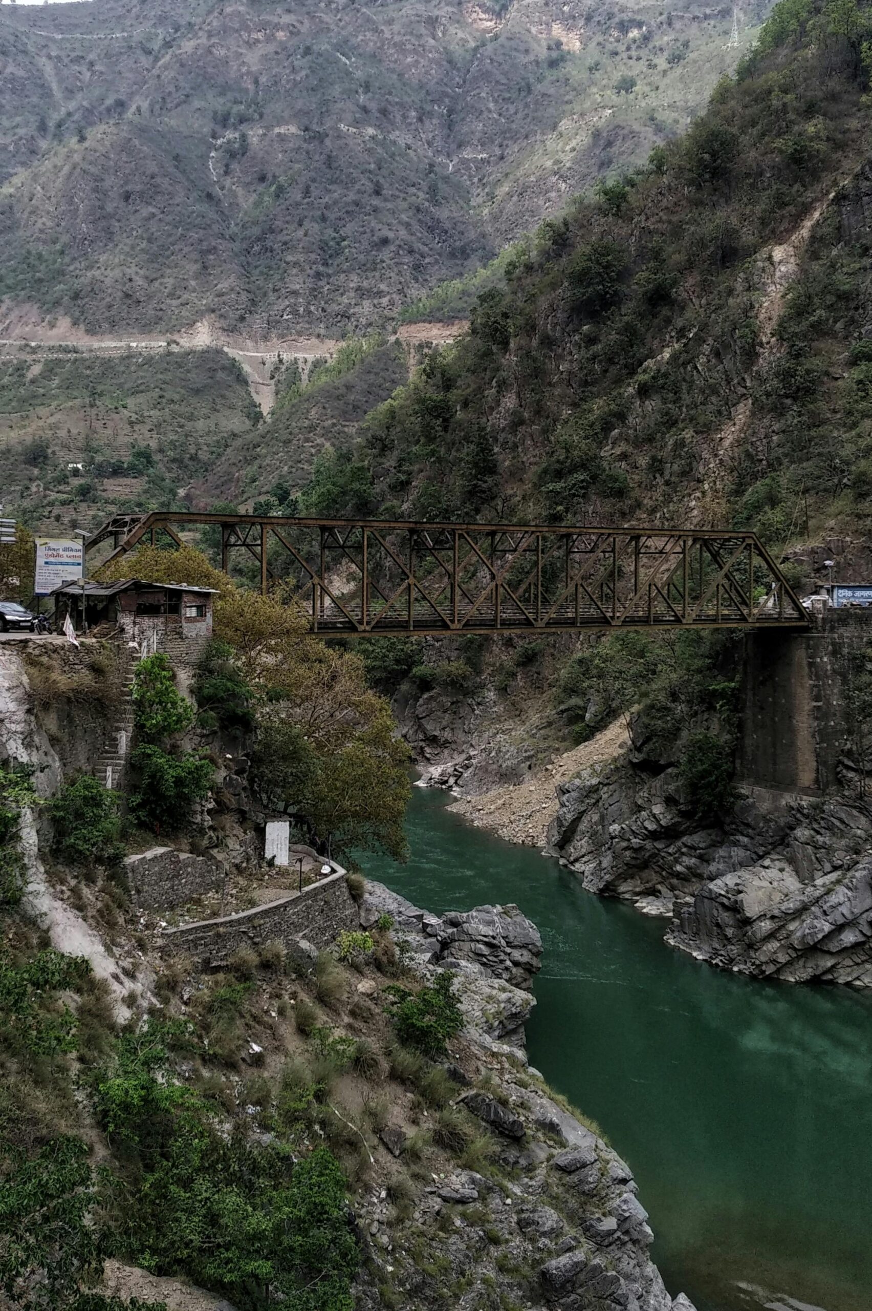 Explore the rustic beauty of a bridge over a river, nestled in the Himalayan mountains.