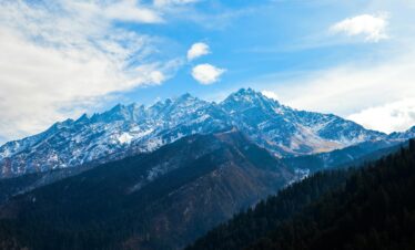 A stunning view of the majestic Dronagiri mountains covered in snow under a clear blue sky.